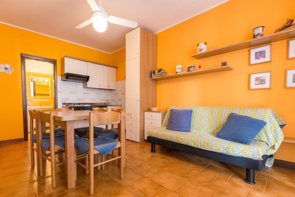 A cozy apartment with vibrant orange walls, wooden furniture, and a cheerful ambiance offers an inviting space for travelers seeking comfort and style in their accommodation.