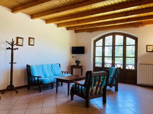A cozy indoor lounge with wooden beams, tiled floors, and arched windows offers a serene retreat, perfect for travelers seeking relaxation in a rustic setting.