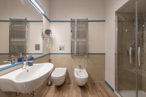 A modern bathroom with sleek fixtures, tiled flooring, and a glass-enclosed shower offers a clean and functional space ideal for travelers seeking comfort and convenience.