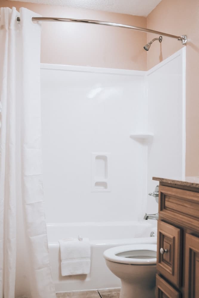 A cozy bathroom with peach walls, white fixtures, and a wooden vanity exudes a warm and inviting atmosphere, perfect for travelers seeking comfort in their accommodations.