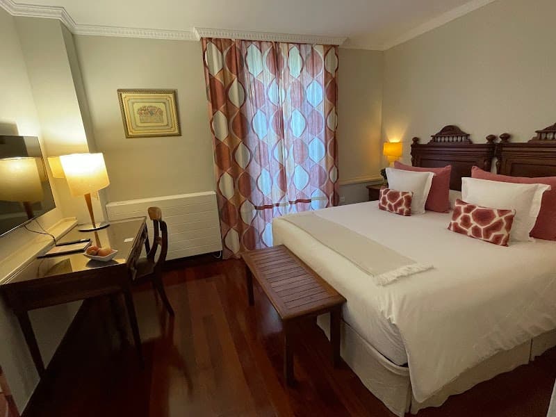 A cozy hotel room in Asturias, Spain, features warm lighting, patterned curtains, and elegant furnishings, creating an inviting atmosphere ideal for travelers seeking comfort and relaxation.