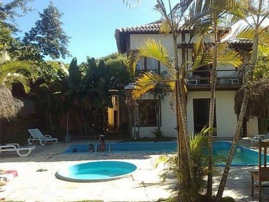 A serene tropical villa with lush palm trees, a sparkling pool, and lounge chairs invites travelers to relax in a private, sunlit paradise ideal for vacation retreats.