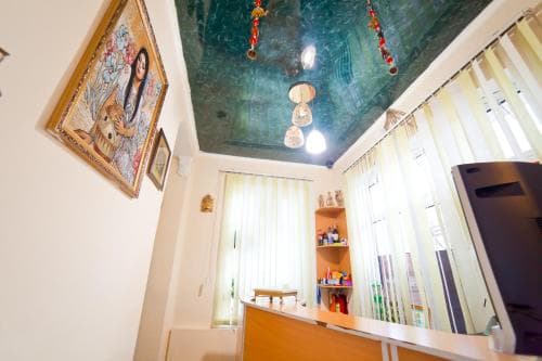 A cozy indoor space features a vibrant ceiling mural, warm lighting, and eclectic decor, creating an inviting atmosphere ideal for travelers seeking a unique cultural experience in a boutique accommodation.