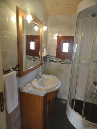 A cozy bathroom with tiled walls, wooden vanity, and a glass-enclosed shower offers a serene retreat, ideal for travelers seeking comfort in compact spaces.