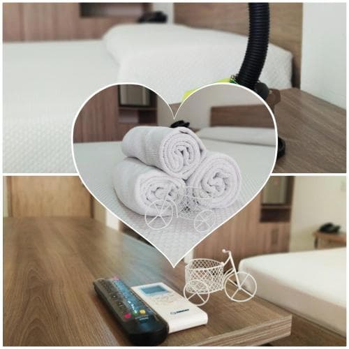 A cozy hotel room scene featuring neatly arranged towels in a heart-shaped frame, a decorative bicycle ornament on the bedside table, and a remote control, evoking a warm and inviting atmosphere ideal for relaxation and leisure travel.