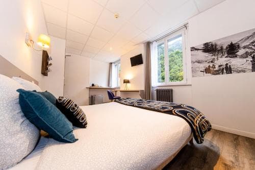 A cozy hotel room with a neatly made bed, soft lighting, and a scenic mountain poster creates a serene atmosphere ideal for travelers seeking relaxation and comfort.