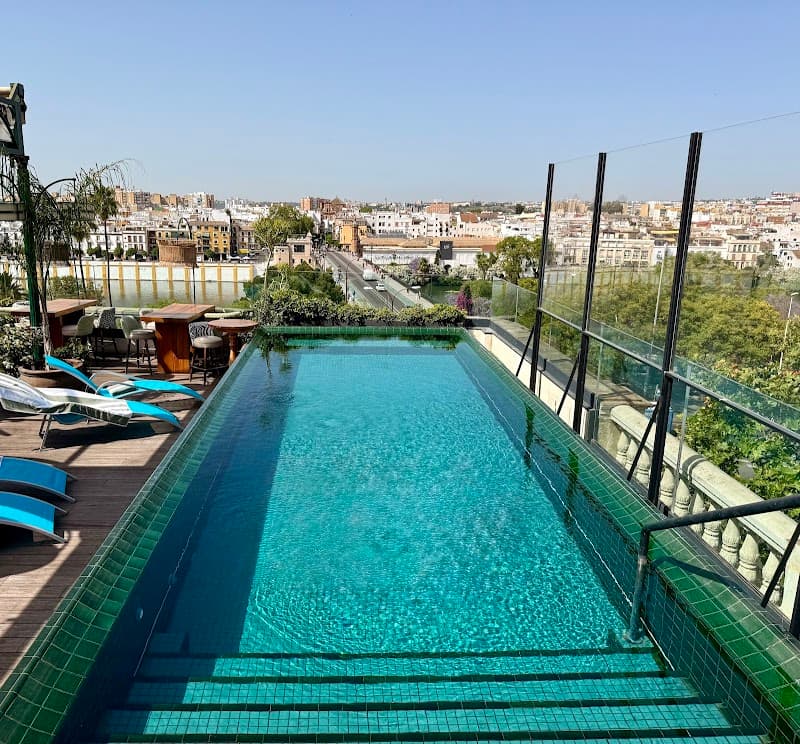 A serene rooftop pool at a hotel in Sevilla's historic Casco Antiguo offers breathtaking views of the cityscape and Guadalajara River, perfect for travelers seeking relaxation and scenic vistas.