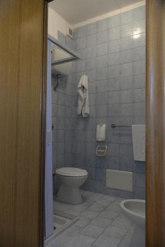 A cozy bathroom with blue tiled walls, white fixtures including a toilet and sink, neatly hung towels, and a wooden door frame, ideal for travelers seeking a clean and functional accommodation space.