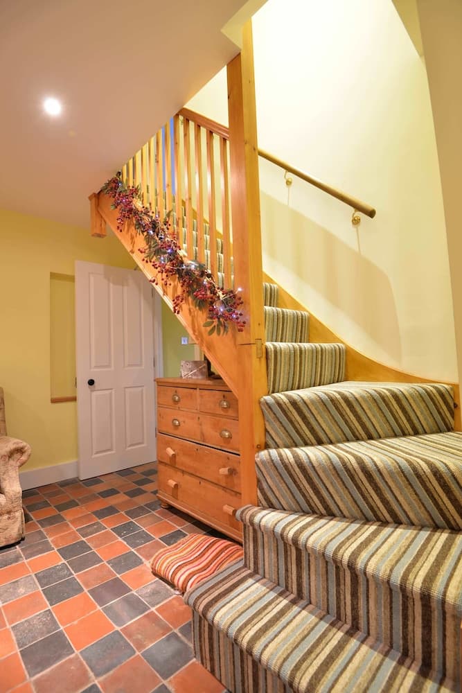 A cozy indoor staircase adorned with festive garlands and striped carpeting creates a warm, inviting atmosphere perfect for home tours or interior design inspiration.