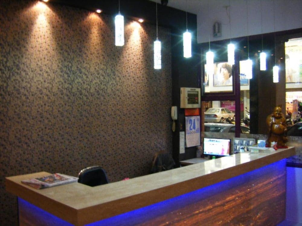 A warmly lit reception area with a textured wall, modern pendant lights, and a sleek counter creates an inviting atmosphere for travelers seeking a comfortable stay or spa services.