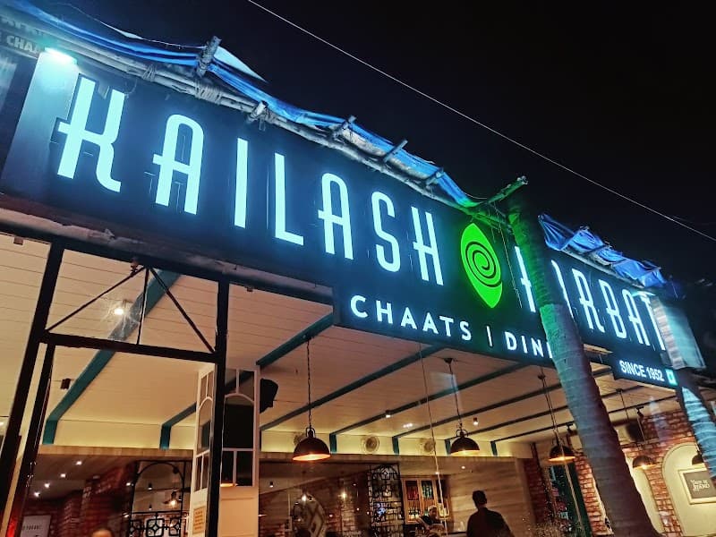A vibrant night scene at Kailash Parbat Chaats | Dining in Goa, featuring a brightly lit signboard, cozy interior ambiance, and inviting travelers to savor traditional snacks in a lively dining spot.