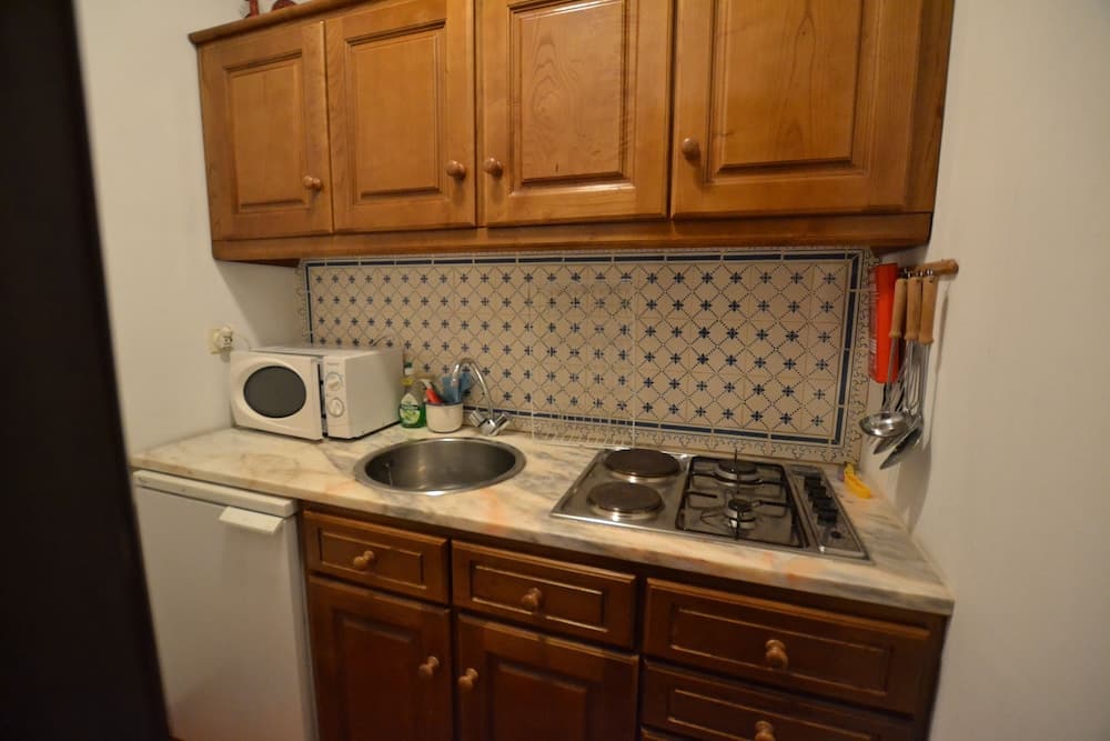 A cozy kitchenette with wooden cabinets, a tiled backsplash, and essential appliances offers a practical space for travelers seeking self-catering accommodations.