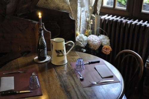 A cozy café table set with a candlelit bottle of wine, floral arrangements, and vintage decor evokes a warm, intimate dining experience perfect for travelers seeking a charming and rustic ambiance.