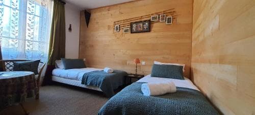 A cozy cabin-style bedroom with wooden walls, two neatly made beds, and soft lighting creates a warm and inviting atmosphere, perfect for travelers seeking a comfortable retreat in a rustic setting.