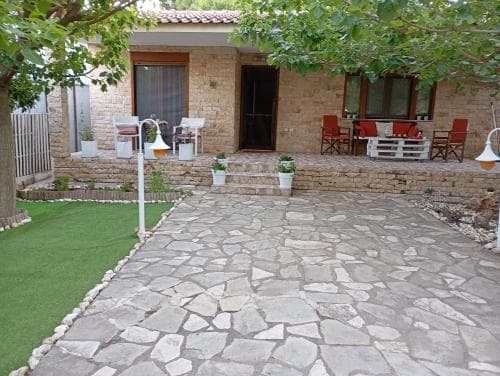A serene stone-paved courtyard surrounded by lush greenery and cozy seating invites travelers to relax in a tranquil vacation retreat setting.