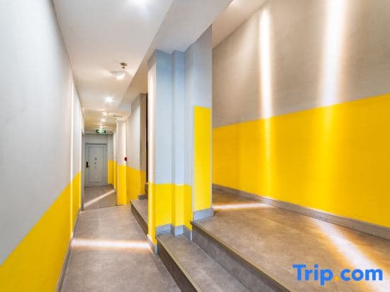A brightly lit hotel corridor with yellow-painted lower walls and steps creates a modern, cheerful atmosphere ideal for travelers seeking a vibrant and welcoming accommodation experience.