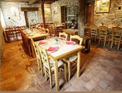 A cozy restaurant with rustic stone walls, wooden tables set with red napkins, and warm lighting creates an inviting atmosphere perfect for travelers seeking a traditional dining experience.