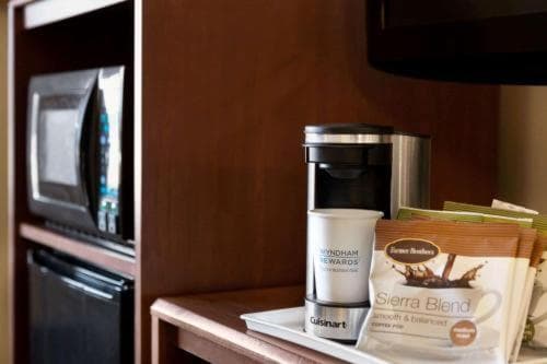 A cozy hotel room kitchenette features a sleek coffee maker with coffee pods, set against warm wood tones, ideal for travelers seeking convenience and comfort during their stay.