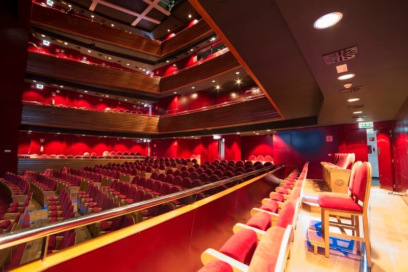 The Teatro Apolo in Miranda de Ebro, Spain, showcases an elegant interior with plush red seats and modern lighting, ideal for travelers seeking cultural performances and theatrical experiences.