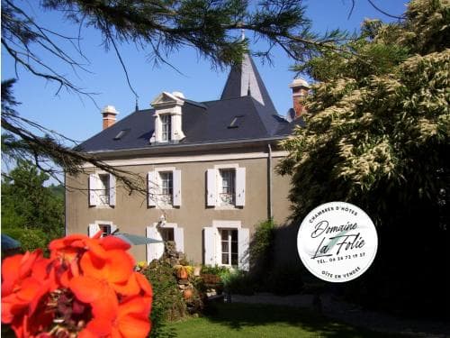 A charming French château-style guesthouse surrounded by lush greenery and vibrant flowers offers a serene retreat for travelers seeking a picturesque countryside escape.