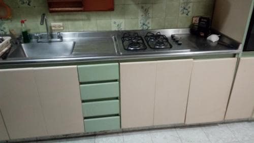 A cozy kitchen with pastel cabinets, stainless steel appliances, and floral tiles exudes a nostalgic charm, perfect for travelers seeking a homey cooking experience.