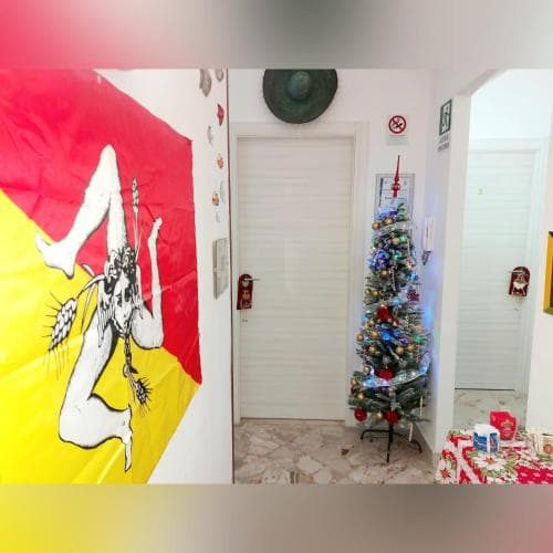 A cozy indoor setting features a festive Christmas tree adorned with ornaments next to a vibrant flag mural, creating a cheerful holiday atmosphere ideal for family gatherings or cultural exploration trips.