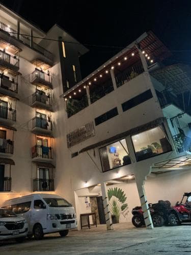 A cozy, well-lit apartment complex at night features balconies adorned with string lights, creating a warm and inviting atmosphere ideal for travelers seeking a comfortable urban stay.