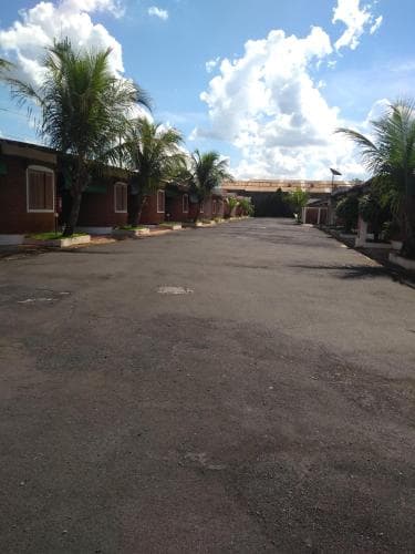 A tranquil tropical motel courtyard lined with palm trees under a bright blue sky, ideal for travelers seeking a peaceful retreat in a warm climate destination.
