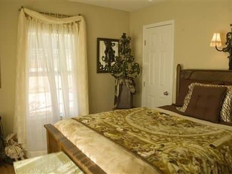 A cozy bedroom with soft lighting, elegant curtains, a decorative mirror, and a plush bed invites travelers seeking comfort and relaxation in a serene indoor retreat.