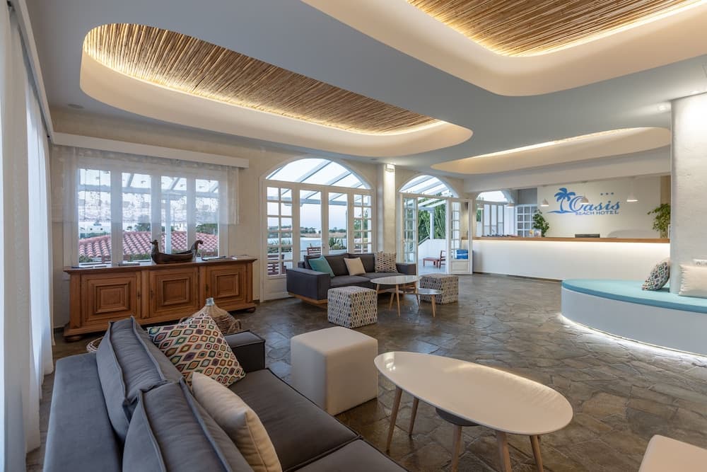A modern beach hotel lobby features stylish seating, warm lighting, and large windows overlooking the ocean, creating an inviting atmosphere ideal for travelers seeking relaxation and comfort.