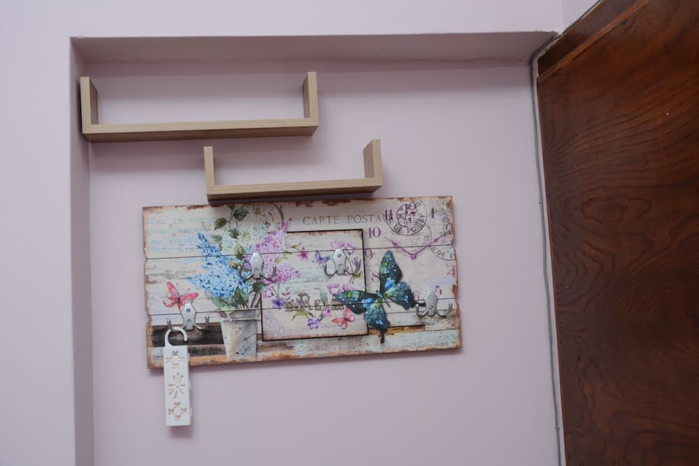 A cozy indoor entryway features a charming butterfly-themed wooden key rack adorned with hooks and shelves, perfect for travelers seeking a quaint and organized accommodation vibe.