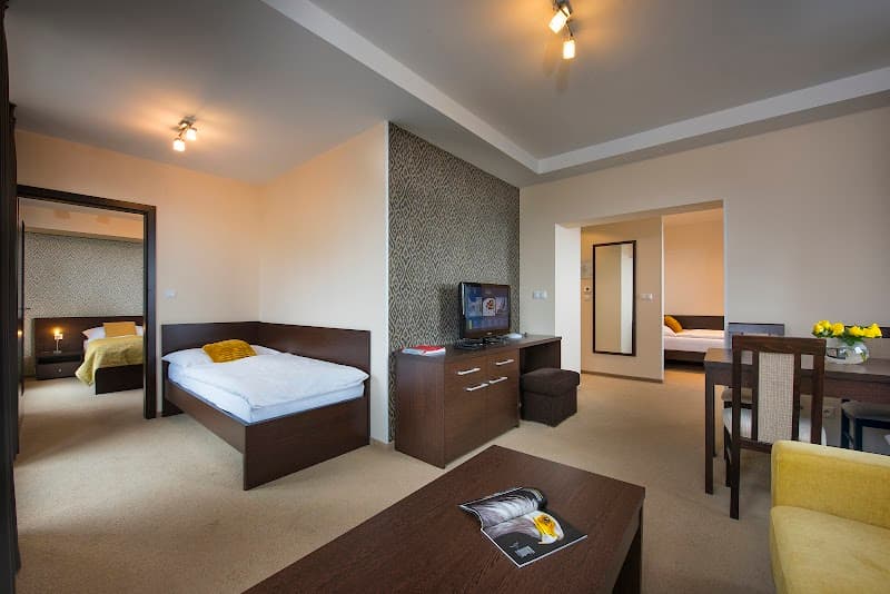 A cozy hotel suite at the Hotel Panorama Resort in Štrbské Pleso, Slovakia, features modern furnishings, warm lighting, and a serene atmosphere ideal for travelers seeking comfort and relaxation.