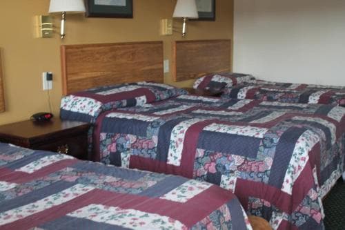 A cozy hotel room features two neatly made beds adorned with colorful floral quilts, set against warm wooden headboards, ideal for travelers seeking comfort and relaxation.