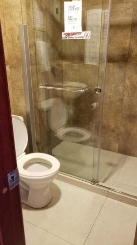 A clean hotel bathroom features a modern glass-enclosed shower and a toilet, creating a functional and hygienic space ideal for travelers seeking comfort during their stay.