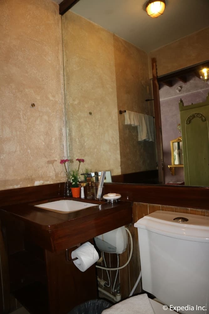 A cozy bathroom with rustic textured walls, wooden vanity, and warm lighting creates an inviting atmosphere, perfect for travelers seeking charm in their accommodations.