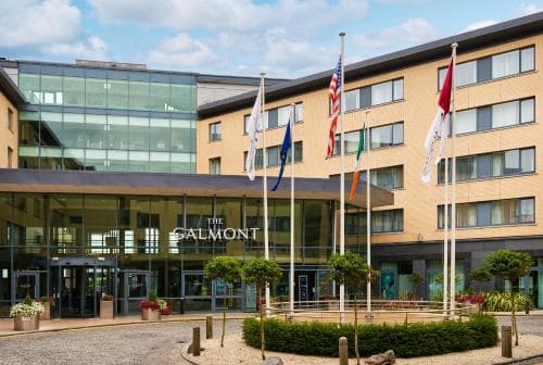 A modern hotel entrance featuring flags from various countries creates a welcoming international atmosphere, ideal for travelers seeking comfortable accommodations in an urban setting.