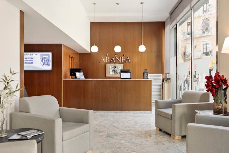 A cozy hotel lobby in Barcelona's Eixample district features modern furnishings, warm wooden accents, and large windows, creating an inviting atmosphere ideal for travelers seeking comfort and style during their stay.