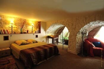 A cozy cave bedroom with warm lighting, stone walls, and comfortable furnishings creates an intimate retreat ideal for romantic getaways.
