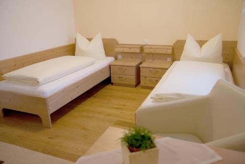 A cozy hotel room features two neatly made wooden beds, simple furnishings, and a small potted plant, creating a warm and inviting atmosphere ideal for travelers seeking comfort and relaxation.