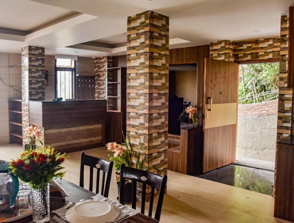 A cozy indoor dining area with wooden furniture, vibrant floral arrangements, and rustic brick columns creates a warm and inviting atmosphere ideal for travelers seeking a comfortable and stylish accommodation experience.