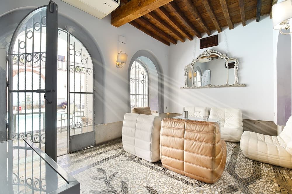 A cozy indoor lounge with leather seating, arched windows, and wooden beams exudes a serene ambiance, ideal for travelers seeking relaxation in a charming heritage setting.