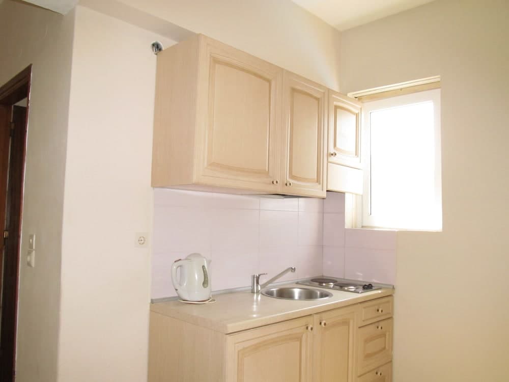 A cozy, minimalist kitchenette with light wooden cabinets, a small sink, an electric kettle, and a bright window, ideal for travelers seeking compact and functional accommodation spaces.
