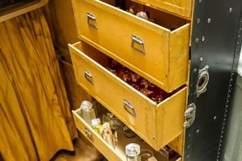 A cozy cabin interior features wooden drawers filled with personal items, evoking a nostalgic mood ideal for travelers seeking vintage-inspired accommodations.
