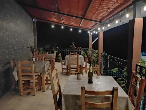 A cozy rooftop terrace at night, featuring wooden tables set under string lights with a bottle of wine on the table, perfect for intimate dinners or romantic getaways.