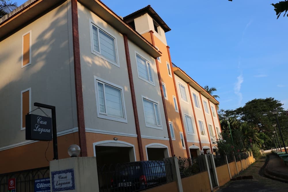 A serene tropical lodging scene features Casa Laguna, a multi-story building with warm hues and lush greenery, ideal for travelers seeking a peaceful retreat.