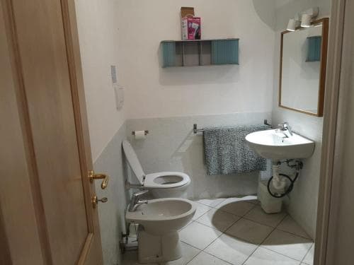A compact bathroom with tiled floors, a sink, toilet, bidet, and bathtub features a cozy and functional design ideal for travelers seeking efficient accommodations.