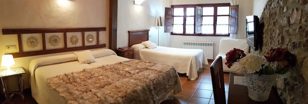 A cozy, rustic hotel room with stone walls, wooden furnishings, and floral accents offers a serene retreat for travelers seeking comfort and charm.