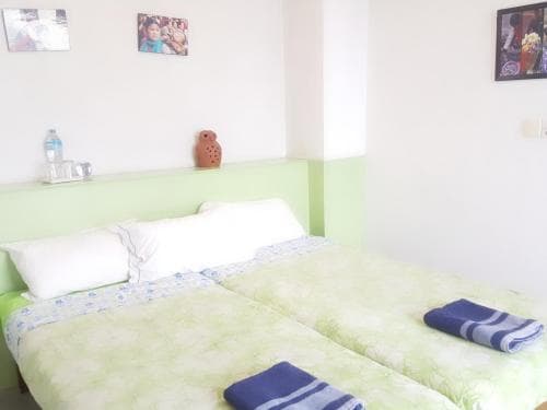 A cozy bedroom with a neatly made bed adorned in green bedding, framed by soft lighting and personal decor, creates an inviting atmosphere ideal for travelers seeking a comfortable and homely accommodation.