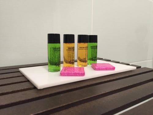 A serene spa setting features vibrant bottles of Rainwater products and pink soap on a sleek tray, ideal for relaxation and wellness retreats.