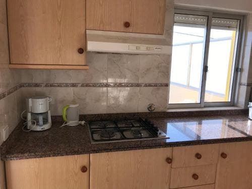 A cozy kitchen with wooden cabinets, tiled backsplash, and a granite countertop featuring a gas stove, kettle, and coffee maker, ideal for travelers seeking self-catering accommodations in an urban setting.
